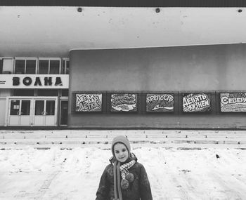 Portrait of smiling young woman standing against wall