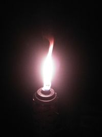 Close-up of lit candle in darkroom