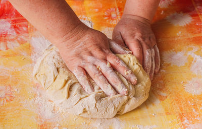 Close-up of woman kneading dough at table