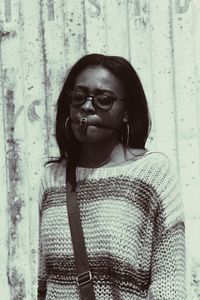 Young woman with padlock on mouth standing against wall