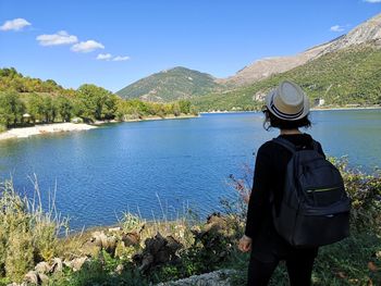 Rear view of man looking at lake against mountain