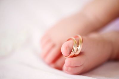 Low section of baby wearing rings on bed