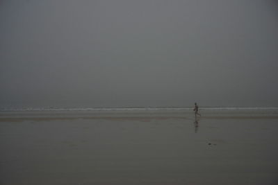 Silhouette man standing on beach against clear sky