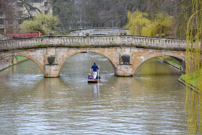 Arch bridge over river against trees