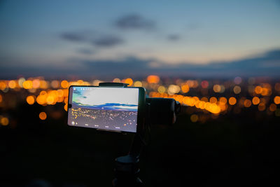 Mobile phone in city against sky at night