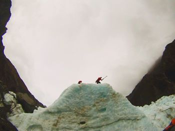 Low angle view of person paragliding against sky