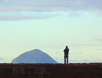 Rear view of man looking at mountain against sky