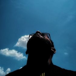 Low angle portrait of silhouette man against blue sky