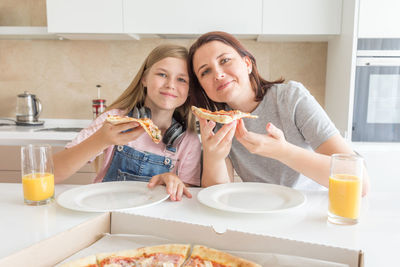 Portrait of mother and daughter eating food at home