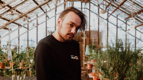 Portrait of young man standing in greenhouse