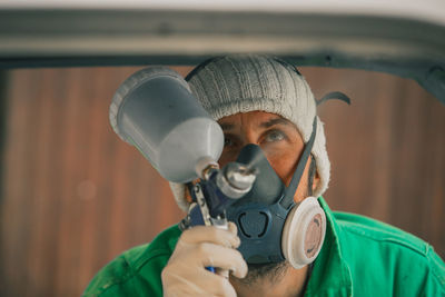 Close-up of man painting while wearing gas mask