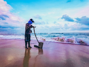 Man photographing at beach against sky