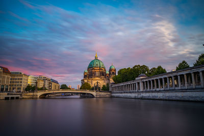 Bridge over river in city against sky