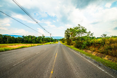 Road amidst plants and trees against sky