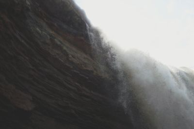 Low angle view of waterfall against clear sky