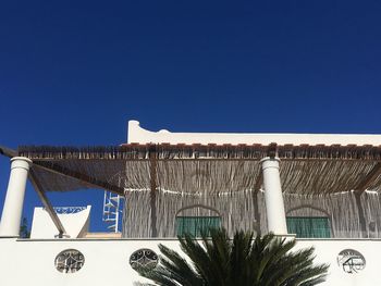 Low angle view of text on building against clear blue sky