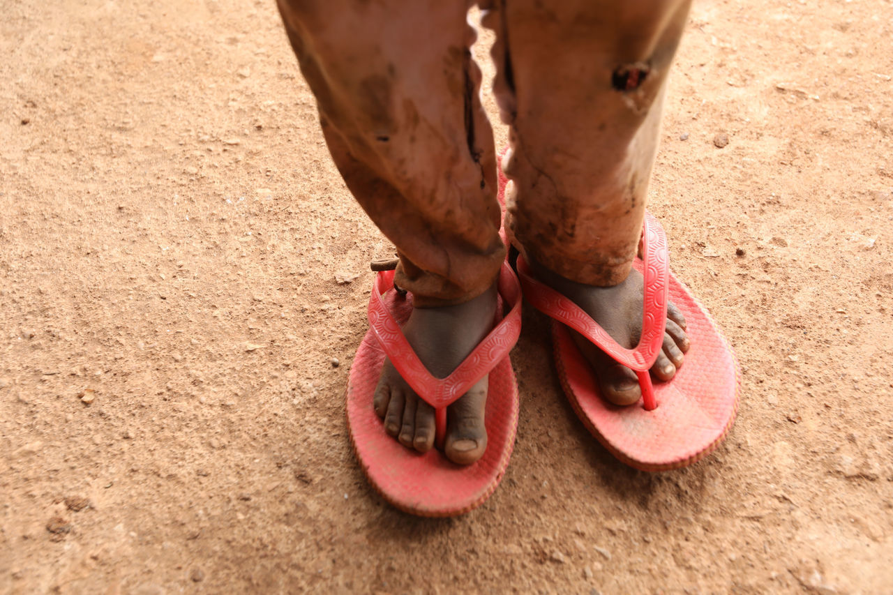 LOW SECTION OF MAN WEARING SHOES STANDING ON SAND