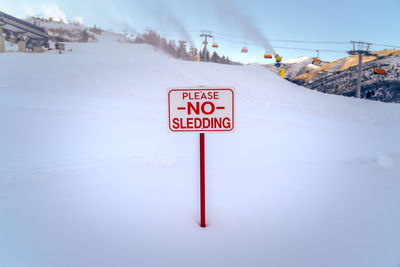 Information sign on snow covered road against sky