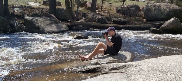 Young woman sitting on rock by sea