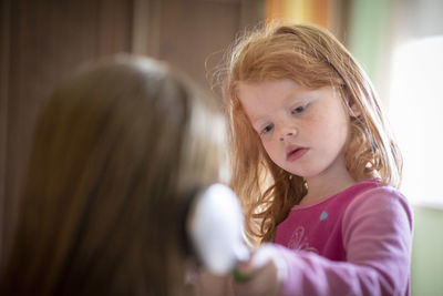 Girl combing hair of mother