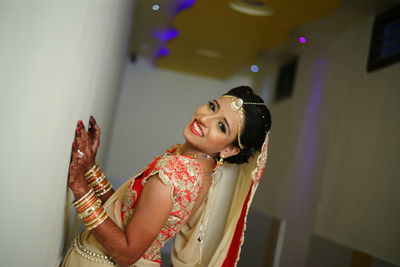 Side view of bride standing by wall in corridor