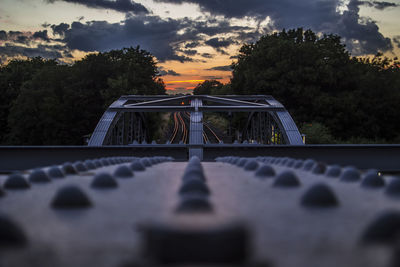 Surface level of bridge against cloudy sky during sunset