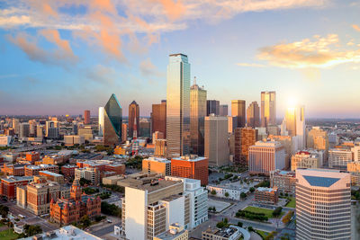 Modern buildings in city against sky during sunset