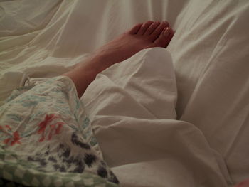 Low section of woman lying on bed