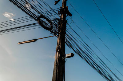 Low angle view of electricity pylon against blue sky