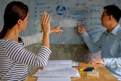 Friends studying with school supplies on table at home