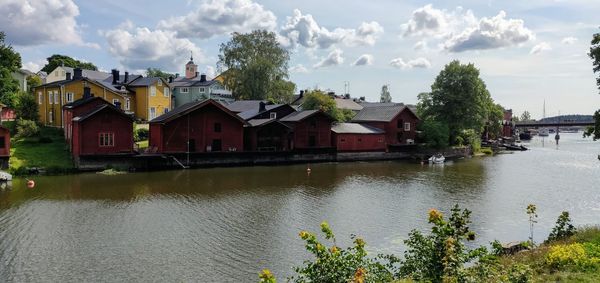 Houses by river and buildings against sky