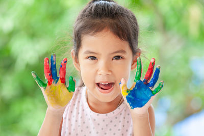 Close-up portrait of smiling girl with painted hands