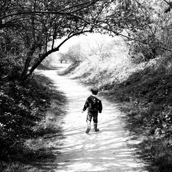 Rear view of people walking on dirt road