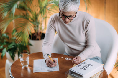 Midsection of man holding paper while sitting on table