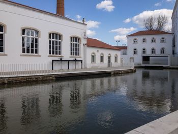 Buildings by canal against sky in city