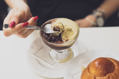 Woman with red nails eating sicilian granita at bar in the summer. brioche blurred in the front.