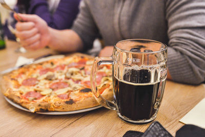 Midsection of man with pizza and drink sitting at table