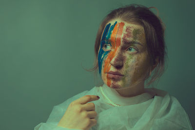 Young woman with painted face against green background