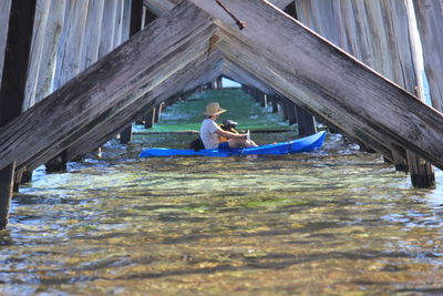 Side view of man with child in boat underneath bridge over sea