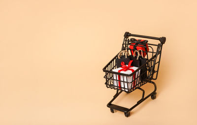 Close-up of shopping cart against pink background