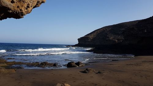 Rocks on beach against clear sky