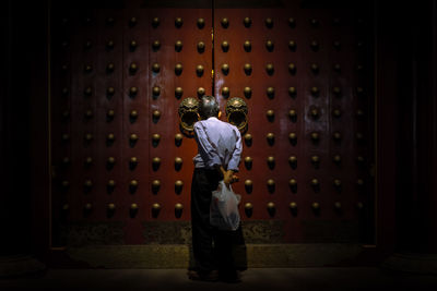 Rear view of man standing against wall in building