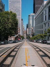 Railroad tracks on street in city during sunny day