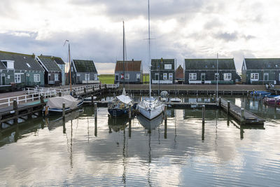 Sailboats moored at harbor against sky in city