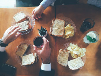 Cropped hands of men eating breakfast on table