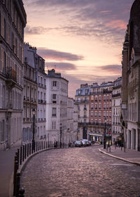 Street amidst buildings against sky during sunset