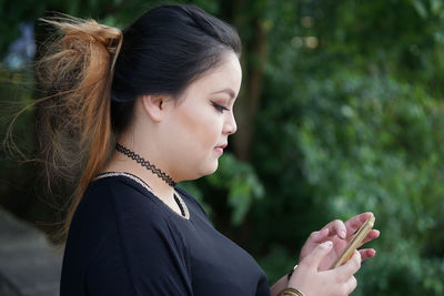 Side view of young woman using mobile