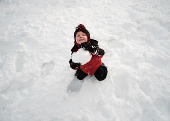 High angle view of cute boy playing in snow during winter