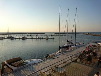 Boats moored by pier against clear sky during sunset