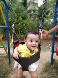 Cheerful baby girl on swing at playground